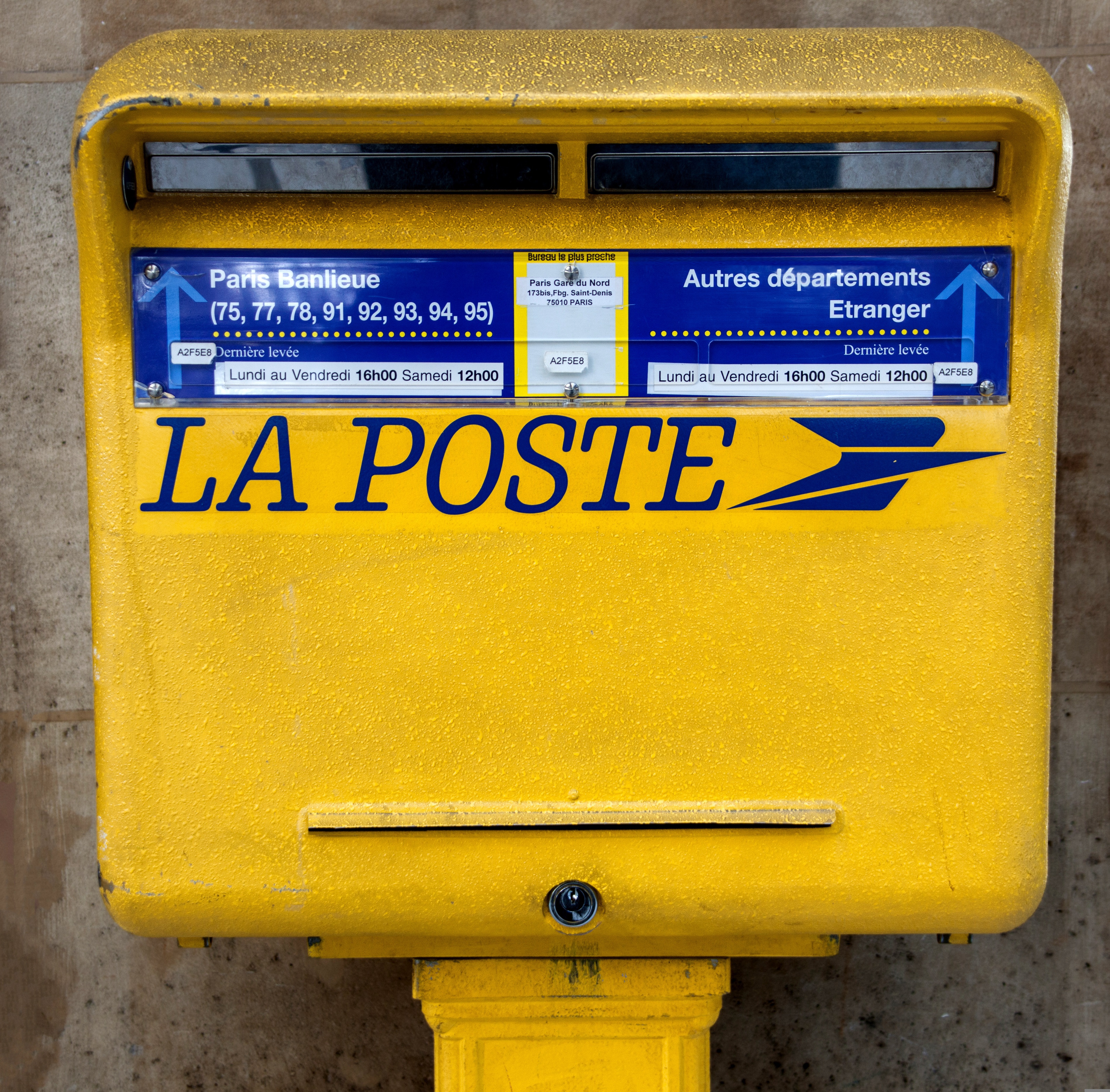 Étiquette d'une boîte aux lettres jaune indiquant les horaires de levée